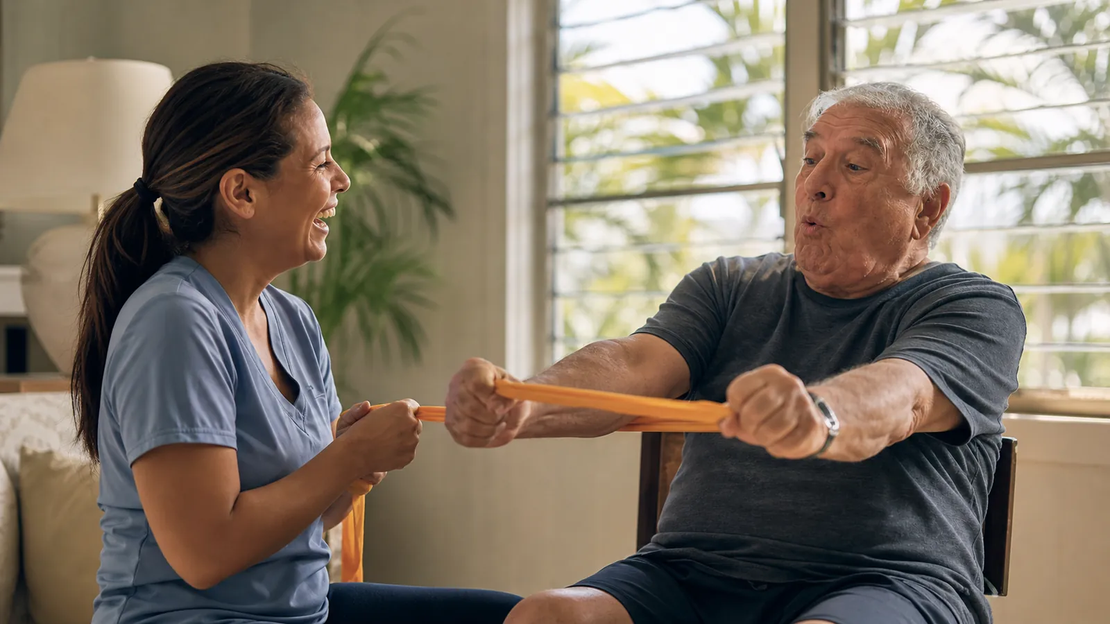 Older man and his aide laughing through balance exercises in his Florida home